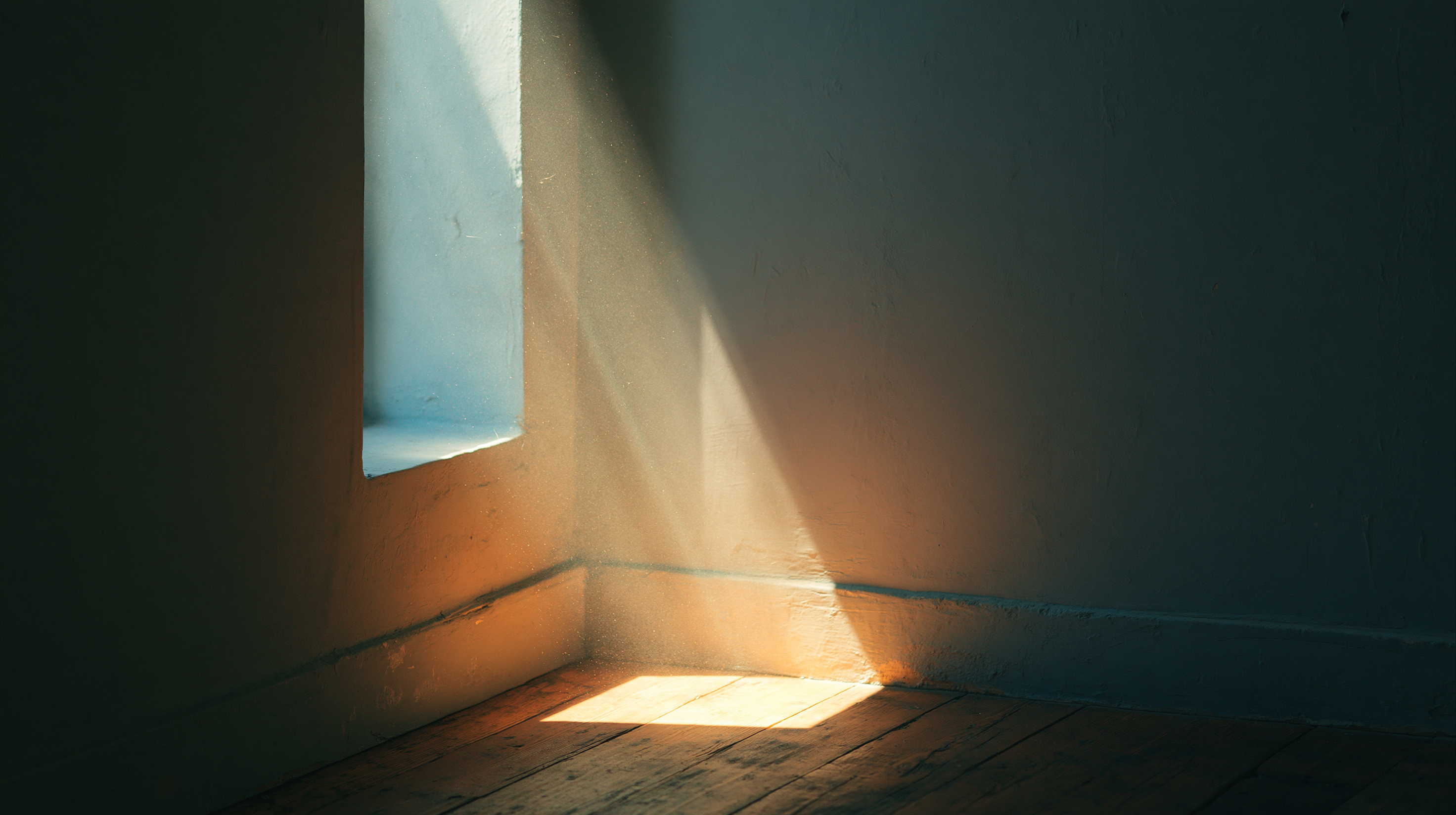 A quiet rectangle of warm light falling across bare wooden floorboards in an empty room.