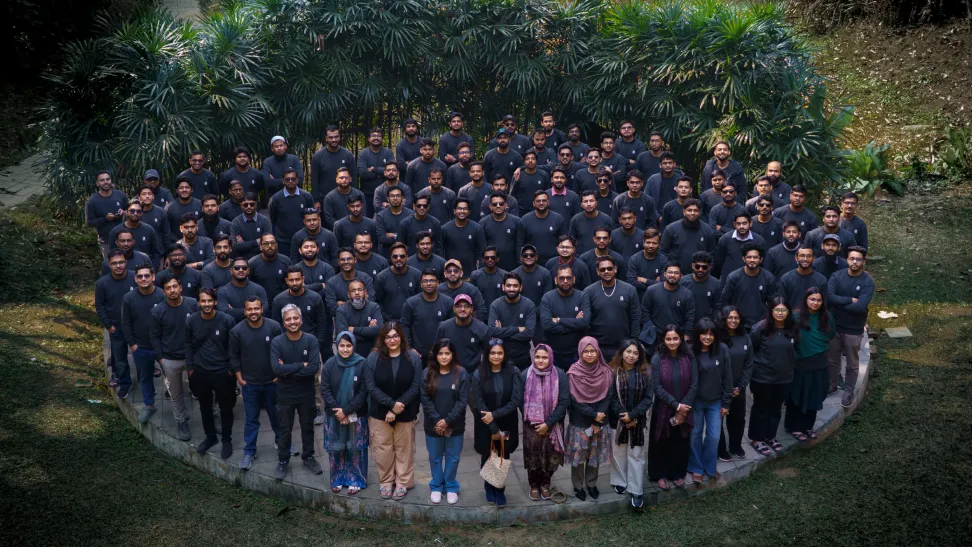 The authLab team in Sylhet, Bangladesh — around 120 people on a circular platform among tropical greenery.
